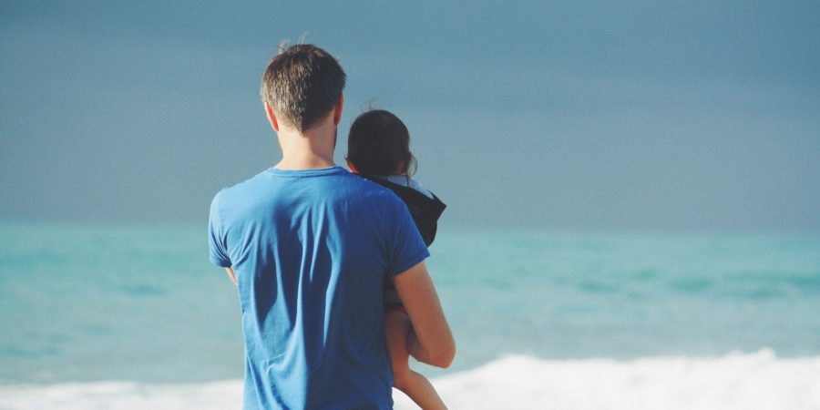 Father holding a daughter looking at ocean